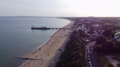 Órbita aérea: ciudad de Bournemouth y muelle en Poole Bay: puesta de sol