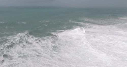 Aerial drone shot of big waves coming into shore on a day with giant waves in Nazaré, Portugal,