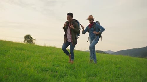 Hikers Traverse Grassy Hillside with Mountain Views