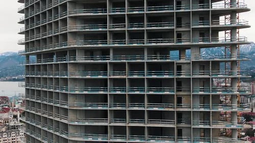 Vertical Panorama of a Tall Building Under Construction Against the Backdrop of the City and