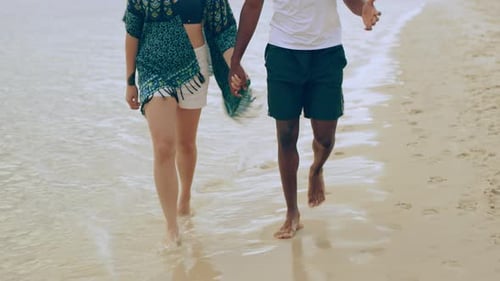 Young couple holding hands enjoying a romantic beach walk in Australia