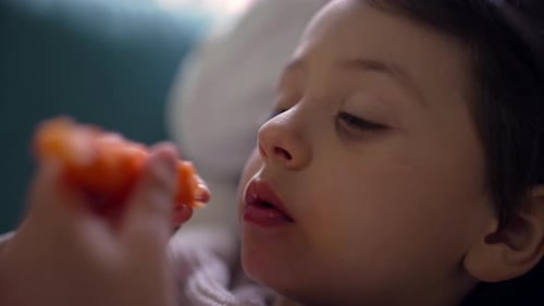 Young child enjoys eating a carrot stick, showcasing healthy eating habits, with a close-up view