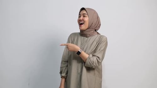 Recommending Asian muslim Woman pointing at right side, copy space. Female presenting, showing