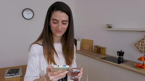 Woman Using Mobile Phone in Bright Kitchen