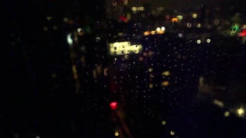 Manchester, Cheshire, Royaume-Uni, il pleut sur une fenêtre la nuit avec des lumières