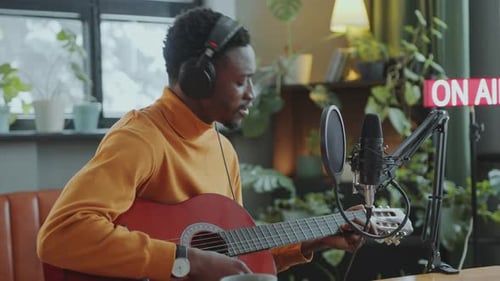 Musiker singt und spielt Gitarre während einer Radiosendung mit einer Moderatorin