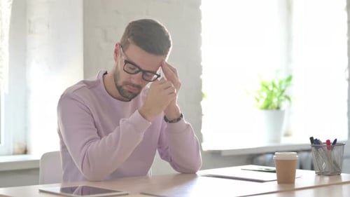 Young Man Having Headache While Sitting in Office