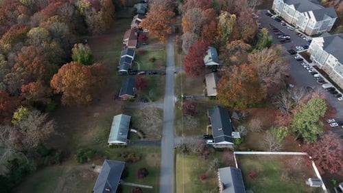Aerial drone view of American suburban neighborhood lined with houses and colorful autumn trees