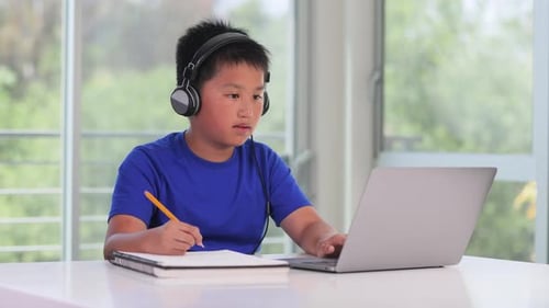 12 year old boy going to school online on his laptop.