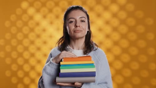 Portrait of Stern Woman Holding Stack of Books Doing Stop Sign Gesturing