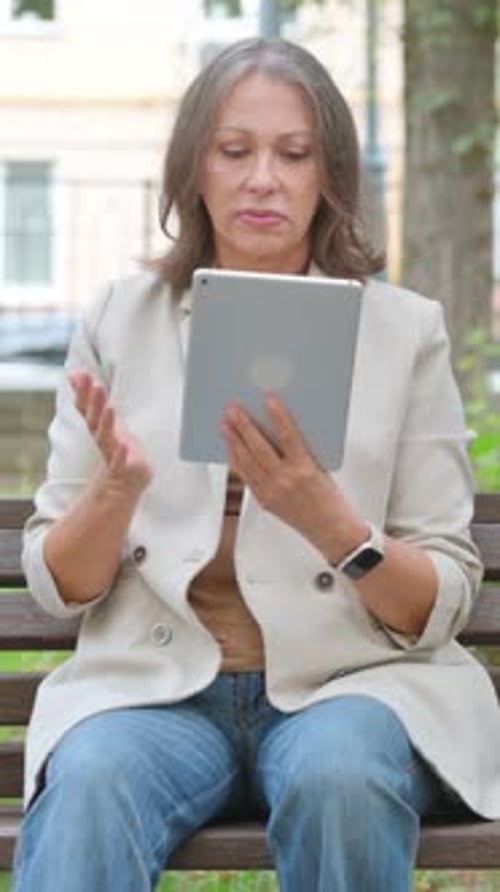 Old Senior Woman with Loss on Tablet while Sitting in Park