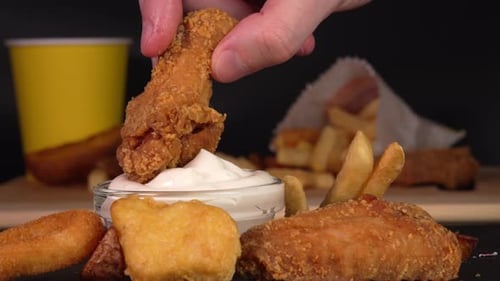 Hand dips crunchy fried chicken wings into garlic sause. Footage for advertise fast food, takeaway