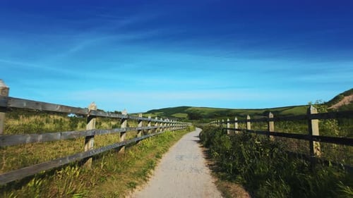 Path Forward is a Gravel Path Between a Wooden Fence with a Magnificent Blue Sky