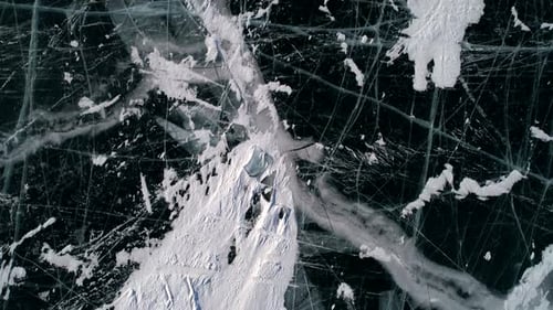 Aerial Above the Blue Transparent Clear Ice with Cracks and Bubbles Inside Frozen Lake Baikal