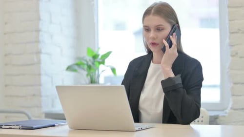 Professional Woman Talking on Phone at Office Desk