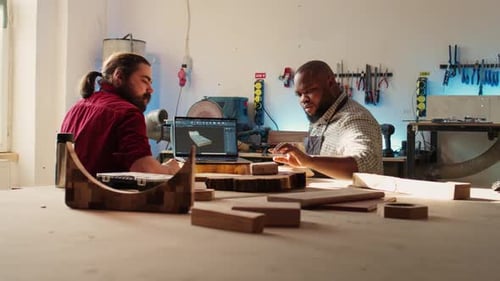 Happy Cabinetmaker and Colleague Comparing Wood Piece with Schematic