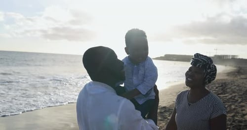 Cheerful African Parents Enjoy Playful Moment with Little Son on the Beach