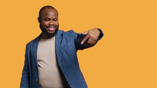Smiling Man Poses with Smartphone on Yellow Background