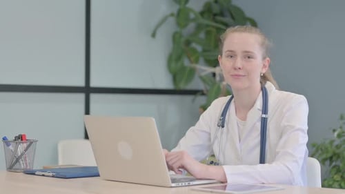 Smiling Woman Doctor Working At Laptop