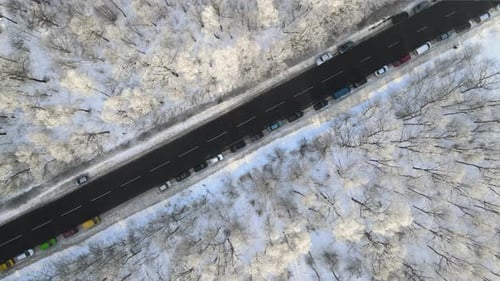 Vue aérienne du paysage hivernal avec des bois enneigés et une route de forêt asphaltée noire sur un hiver froid