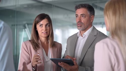 Busy Business Executives Team Discuss Digital Strategy Using Tablet in Office