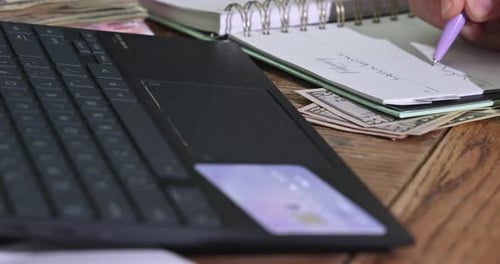 Hand Writes in Notebook by Laptop and Cash