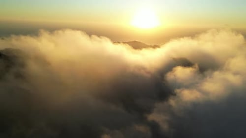 Sunrise flight over the clouds and mountains