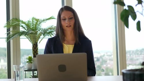 Professional Woman in Office Using Laptop for Meeting