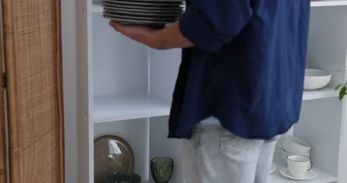 Homme mettant des assiettes sur une étagère à l'intérieur, gros plan