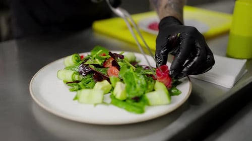 Gros plan d'un chef masculin confiant plaçant les derniers morceaux de légumes et de poisson sur une salade