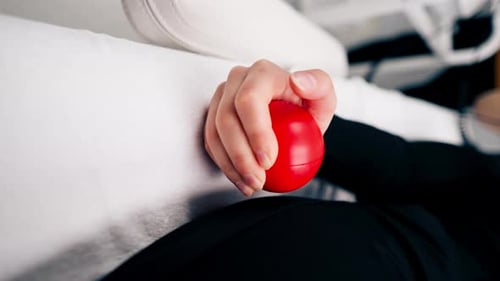 vertical video close-up of a woman's hand squeezing an anti-stress ball toy during a painful