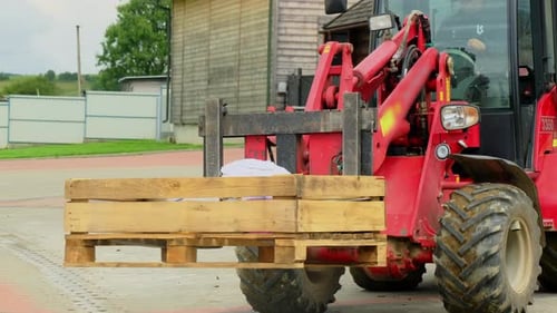 Roter Gabelstapler transportiert Holzpaletten im Lagerhof