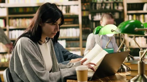 Studentin macht sich Notizen am Bibliothekstisch und forscht