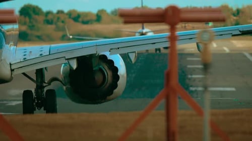 Verkehrsflugzeug wärmt Turbinen auf der Landebahn auf, während im Hintergrund ein anderes Flugzeug im Passagierjet startet