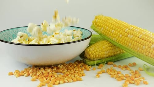 Grains de pop-corn tombant dans un bol en céramique isolés sur fond blanc