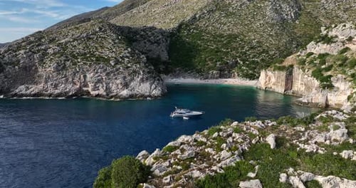 Yacht Anchored in Beautiful Cove - Aerial Orbit with Cliffs Foreground
