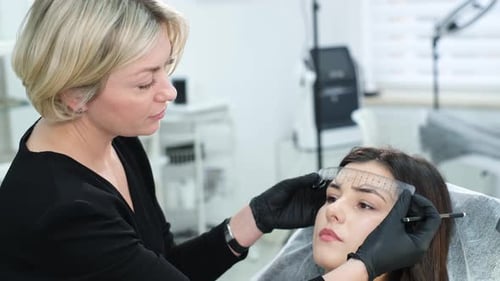Cosmetologist Measuring Eyebrows in Bright Salon