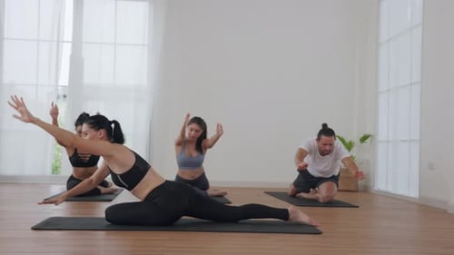 Group Yoga Class in a Bright Studio Practicing Seated Stretching Poses