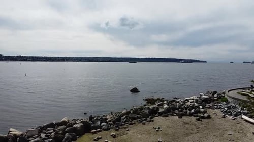 Aerial fly over seawall park by the ocean where boats are in the rocky harbor on a low tide scenic s