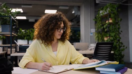 Young Female Student Taking Notes in a Modern University Library