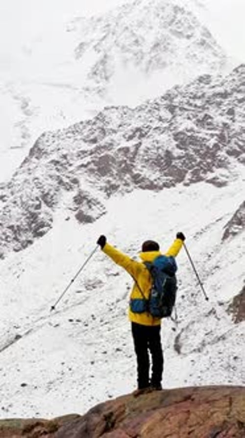 Hiker Celebrating Reaching the Summit in the Snowy Mountains