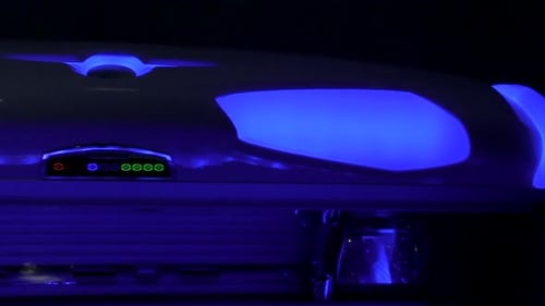 KBL Tanning Bed Lid With Blue Light And Power On - close up, panning left shot