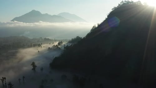 Beautiful tropical valley between mountains. The rays of sunrise break through the clouds and glow o