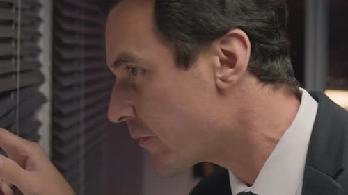 Man Talking on Walkie Talkie Looking Through Blinds