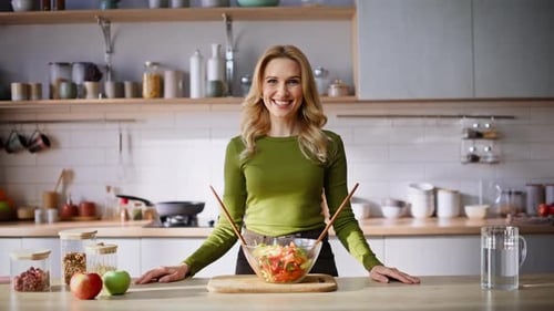 Smiling Woman with Salad in Bright Kitchen