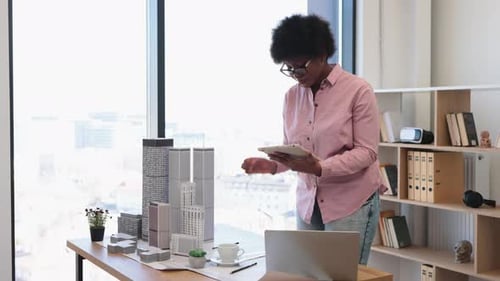 Arquitecto afroamericano trabaja en un modelo de ciudad con tableta digital