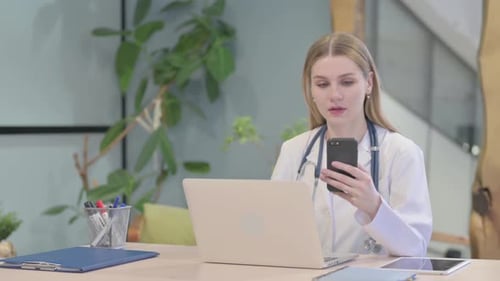 Young Woman Doctor Using Smartphone and Laptop