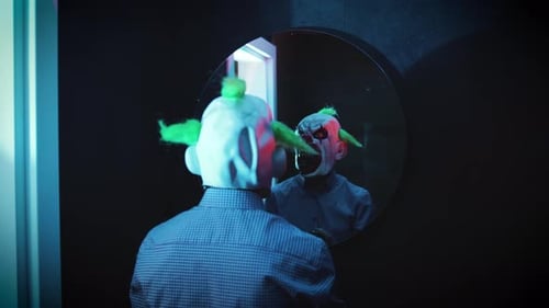 Terrifying Clown in Striped Shirt in Front of Mirror with Flashing Lights