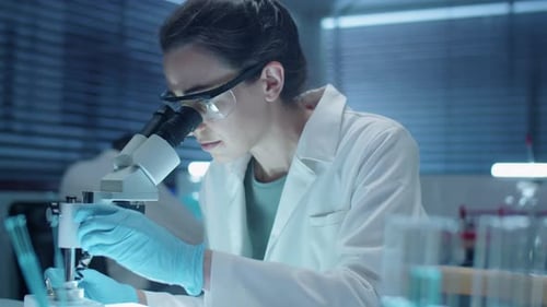 Focused Scientist Using Microscope in Modern Laboratory