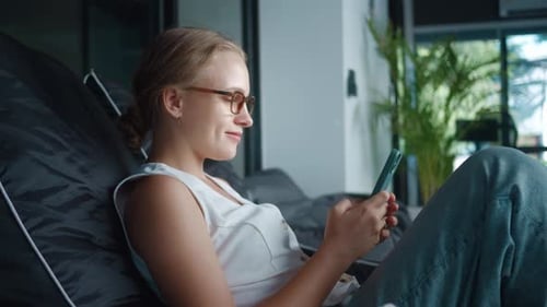 Woman Relaxing Using Smartphone on Beanbag Chair